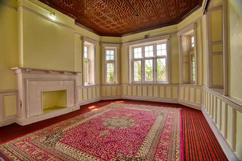 A spacious, elegant room with large windows, fireplace, and vibrant carpet in Jammu and Kashmir.